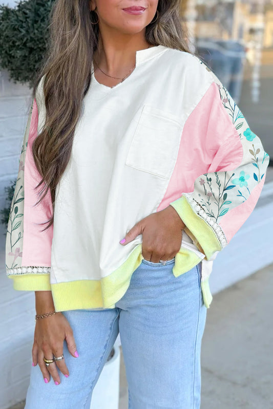 Woman wearing a white blouse with floral sleeves and light blue jeans outdoors.